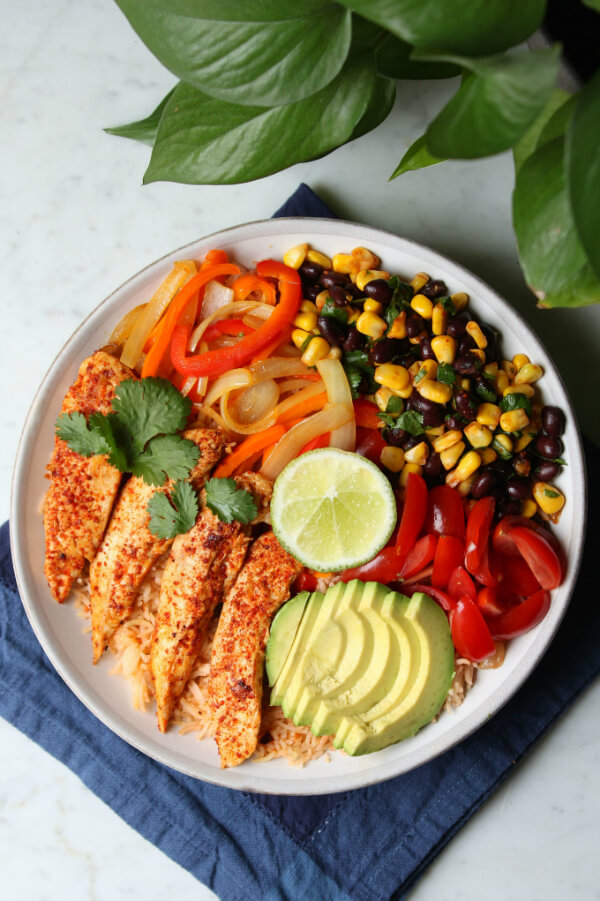 Simply Delicious Chicken Burrito Bowl - a bowl filled with chicken, rice, peppers, avocado, corn and beans.