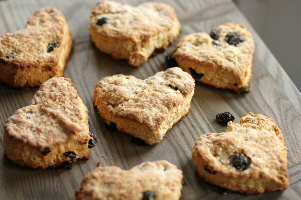 Cranberry Lemon Scones - Heart Shaped golden baked scones studded with red cranberries on a wooden board.