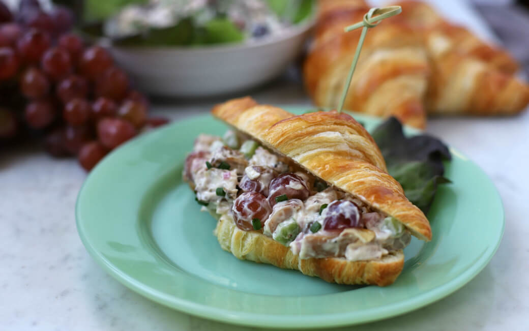 Close up of a croissant filled with smoky chicken salad.