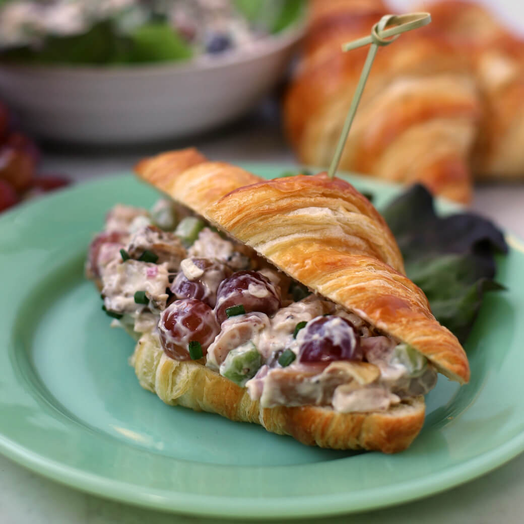 Close up of a croissant filled with smoky chicken salad.