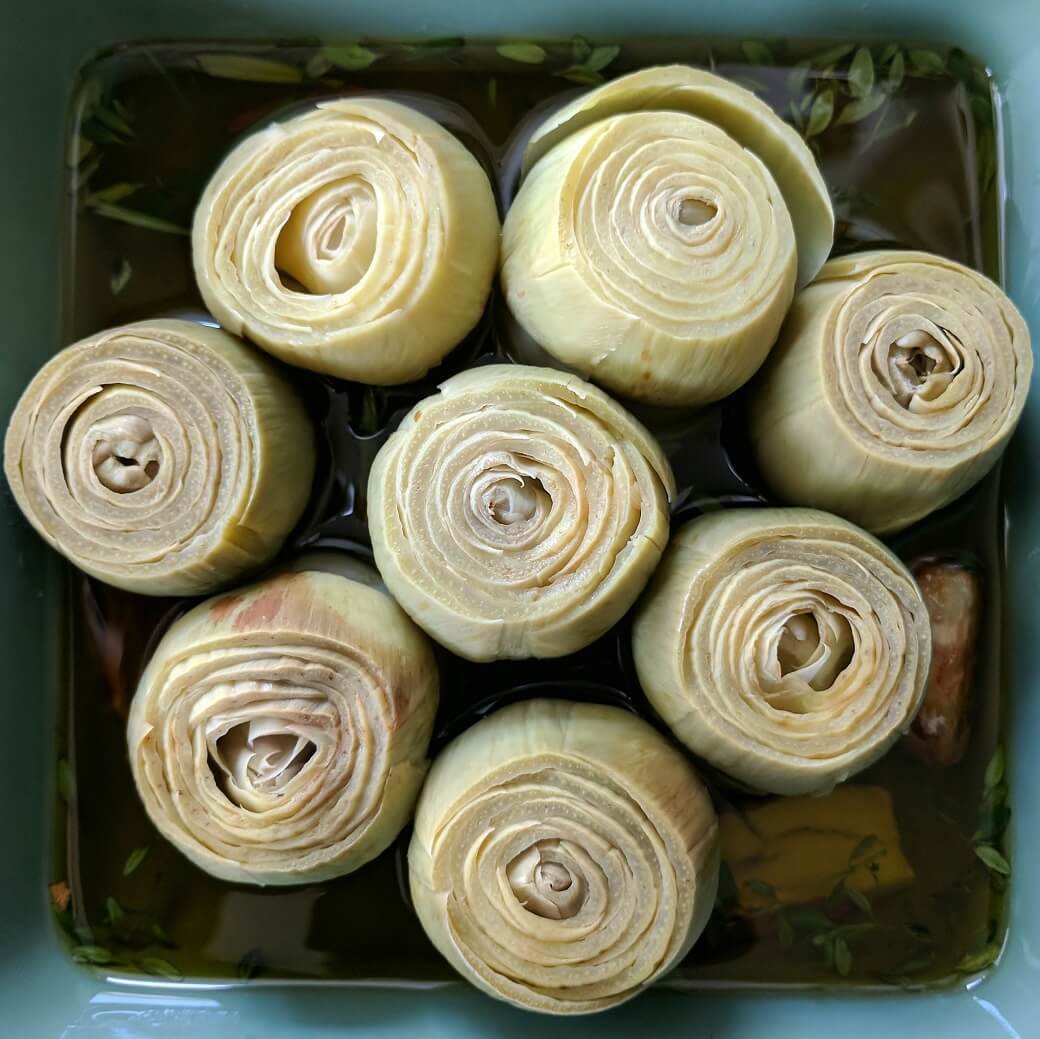 Prepared baby artichokes in a baking dish.