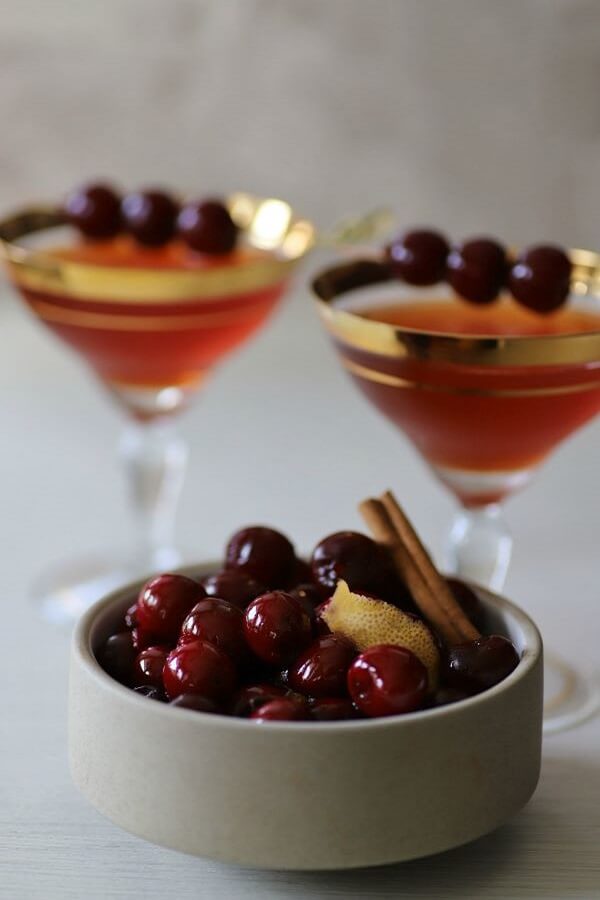 Two Manhattan Cocktails place behind a bowl of cherries.