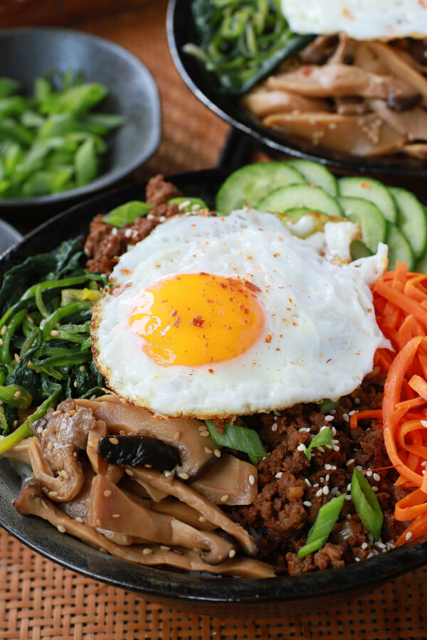 A bowl of vegetables and ground beef topped with an egg.