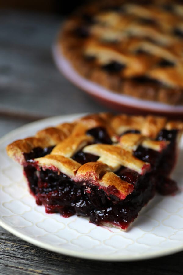 A slice of cherry pie with golden baked lattice top.