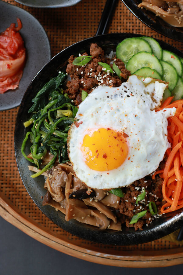 A bowl of vegetables and ground beef topped with an egg.