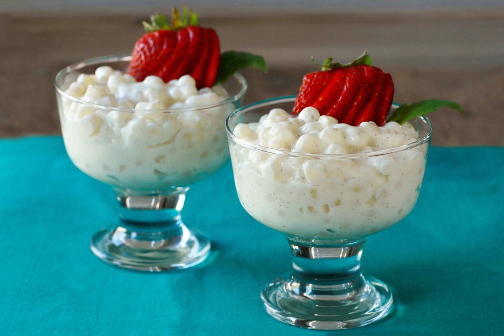 Two glass dessert bowls filled with creamy tapioca pudding topped with sliced strawberries.