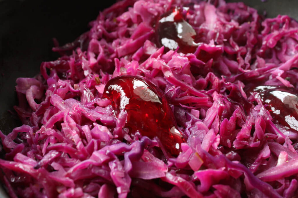 Bright purple shredded red cabbage with a scoop of red jelly.