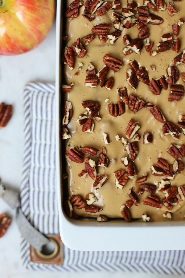 A white cake pan filled with cake topped with brown butter glaze and pecans.