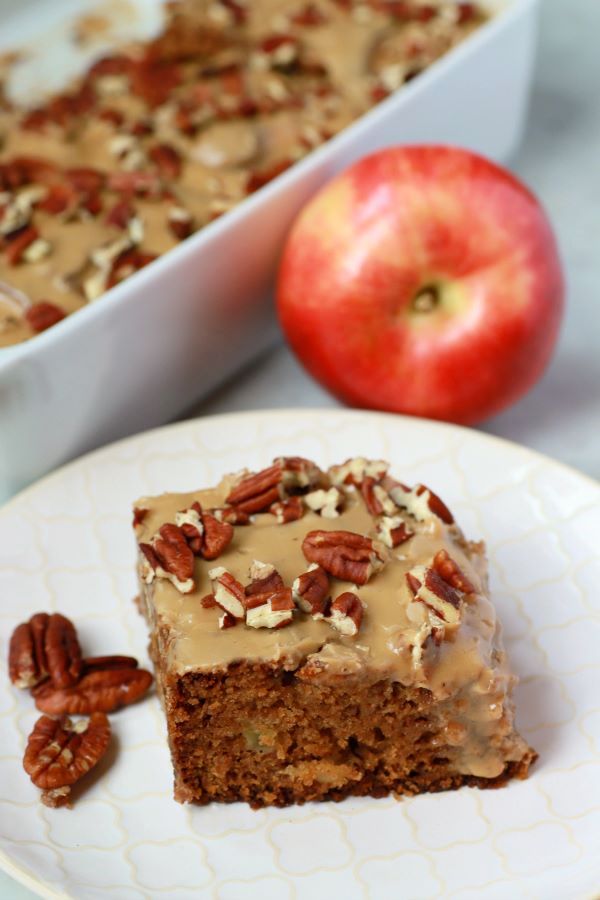 A slice of chunky apple cake topped with brown sugar glaze and pecans.