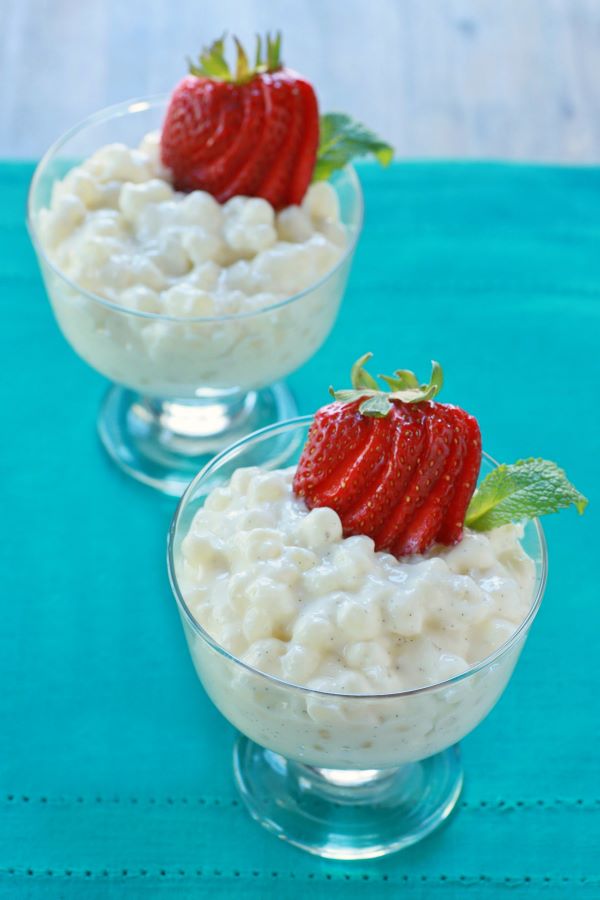 Two glass dessert bowls filled with creamy tapioca pudding topped with sliced strawberries.