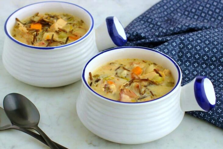 Two white bowls filled with creamy chicken wild rice soup.