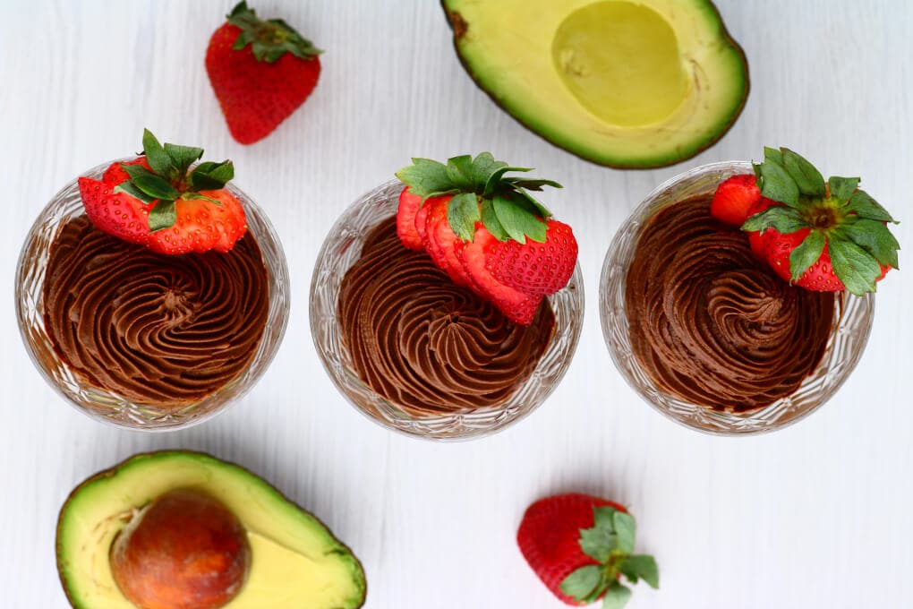 Crystal glasses filled with dark chocolate avocado mousse topped with a strawberry.