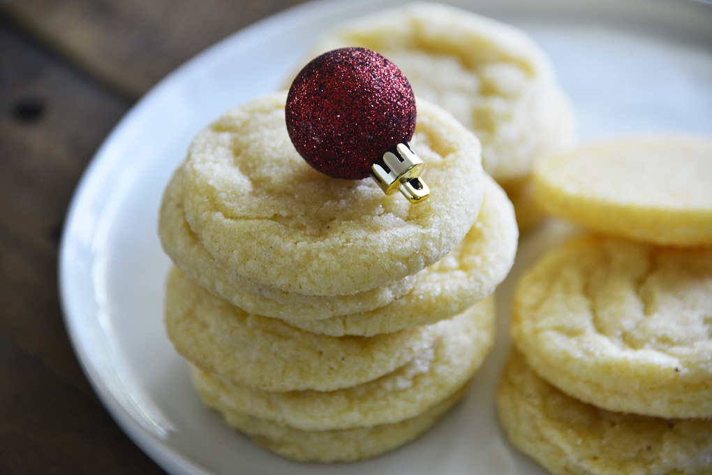 Eggnog Cookies stacked on a white plate with Christmas ball decorations.