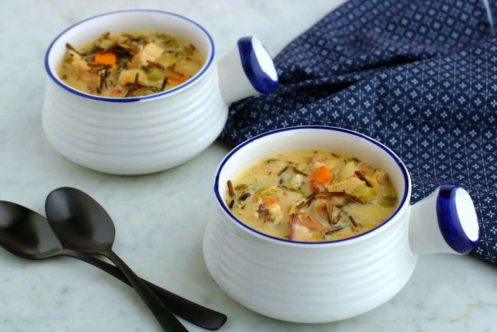 Two white bowls filled with creamy chicken wild rice soup.