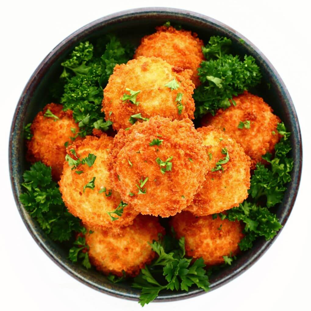 Overhead view of a blue bowl filled with golden fried goat cheese balls.