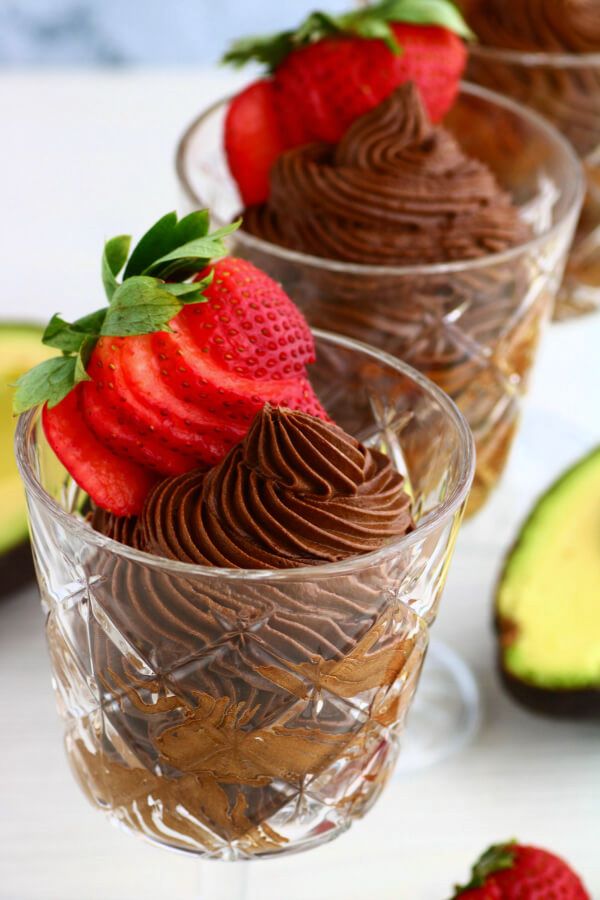 Crystal glasses filled with dark chocolate avocado mousse topped with a strawberry.