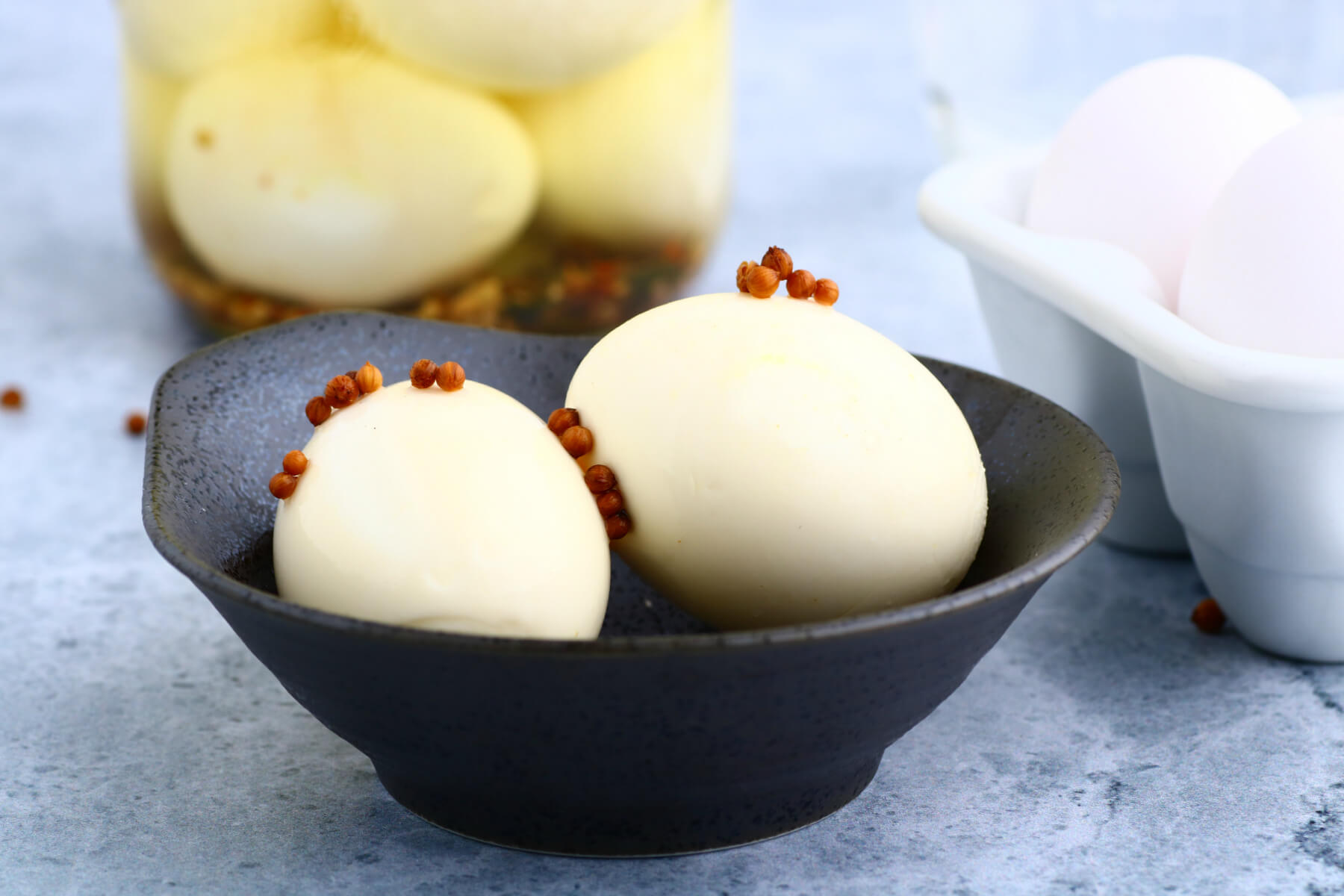 Two hard boiled pickled eggs in a dark bowl.