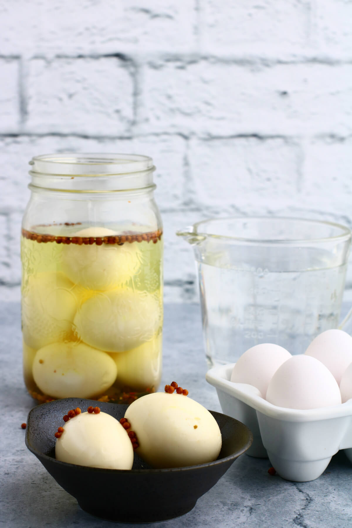 Hard boiled Pickled eggs in a jar with a bowl of eggs in foreground.