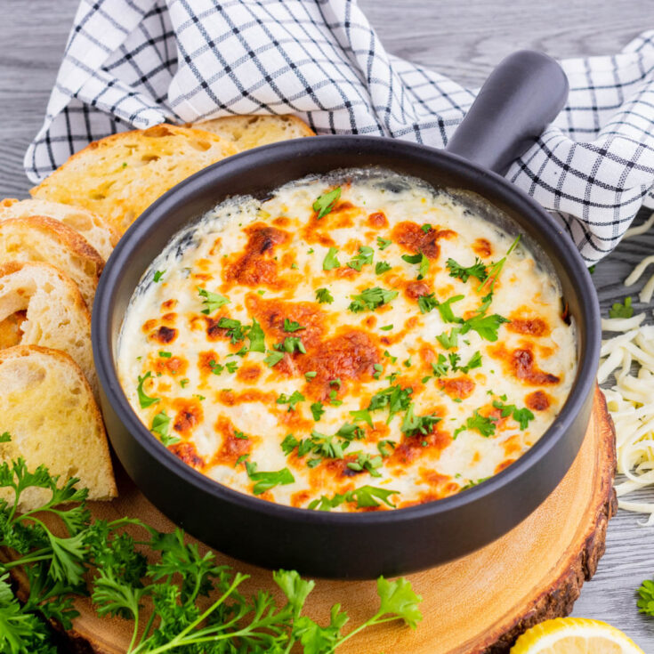 Golden cheese topped dip in a black baking dish.