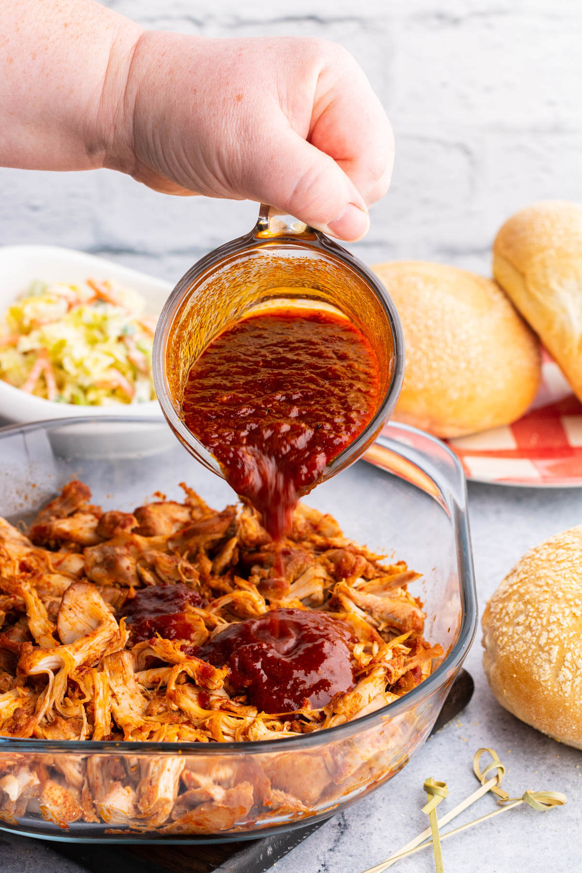 Pouring BBQ Sauce over shredded chicken.