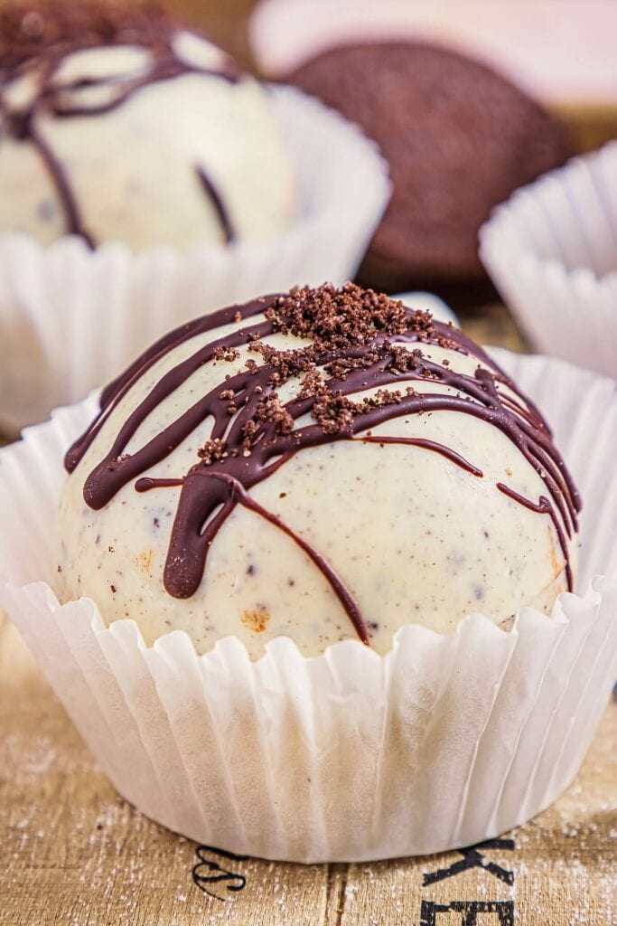 A chocolate bomb decorated with cookie crumbs and dark chocolate.