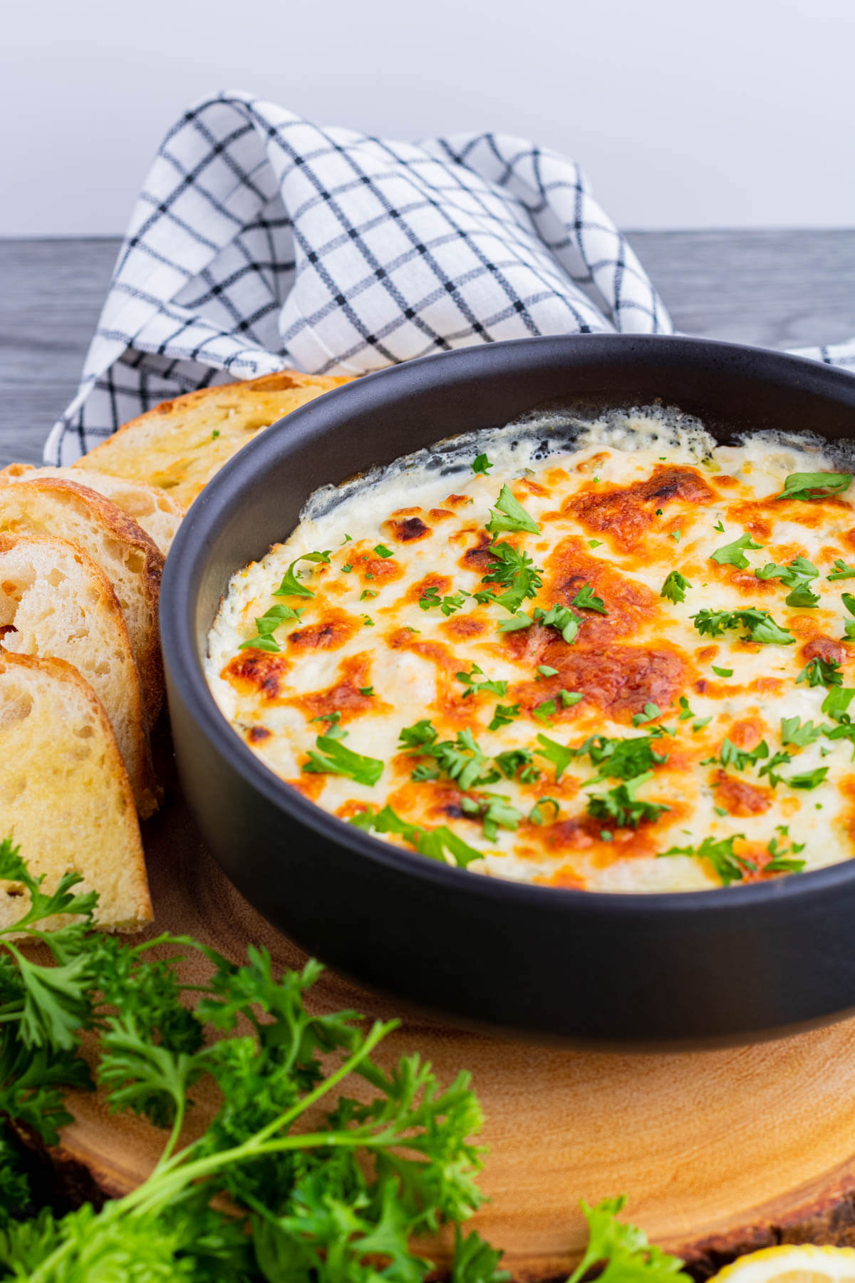 Close up of hot golden baked cheese dip with sliced baguette.