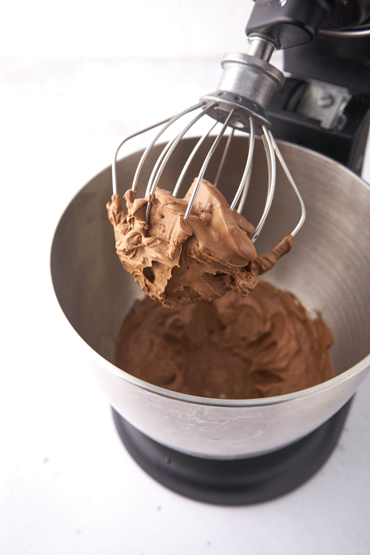 Chocolate frosting on the whisk of a stand mixer.