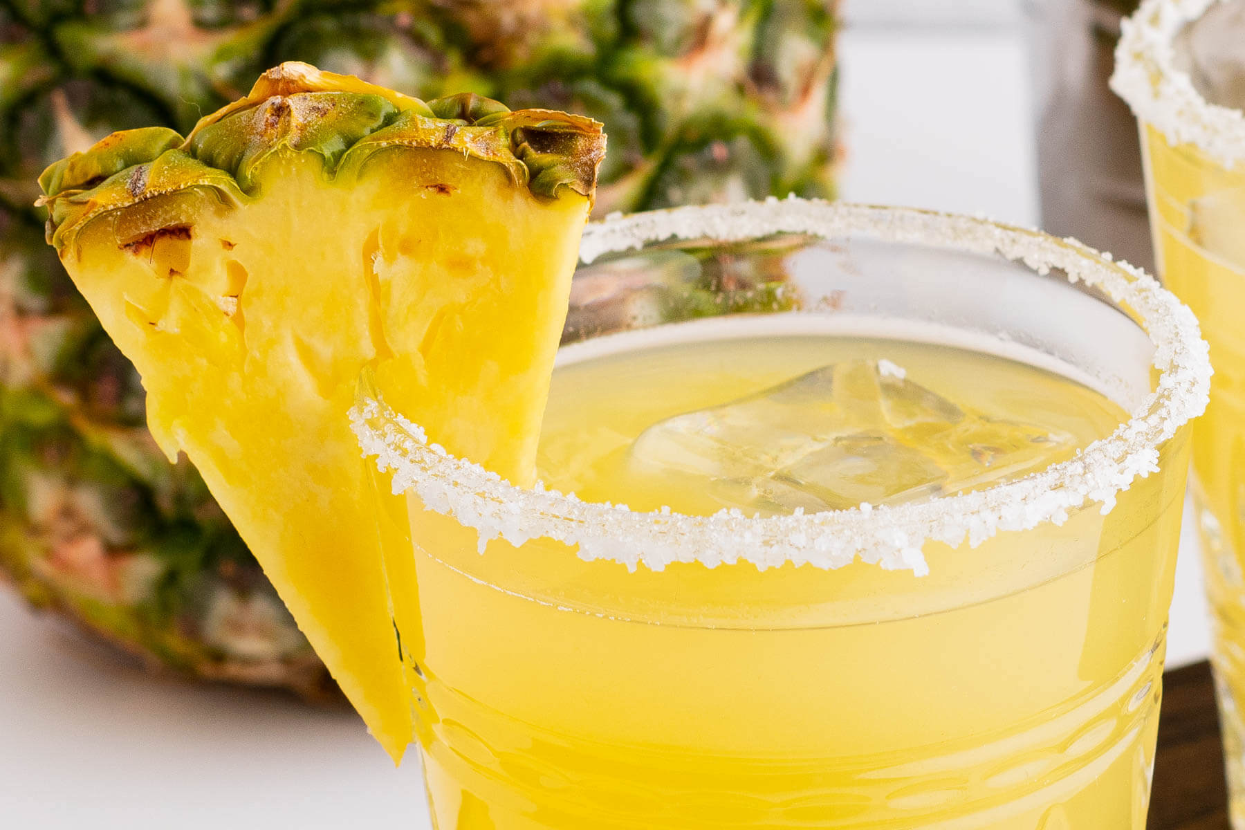 Close up of a margarita in a glass with rimmer and pineapple garnish.
