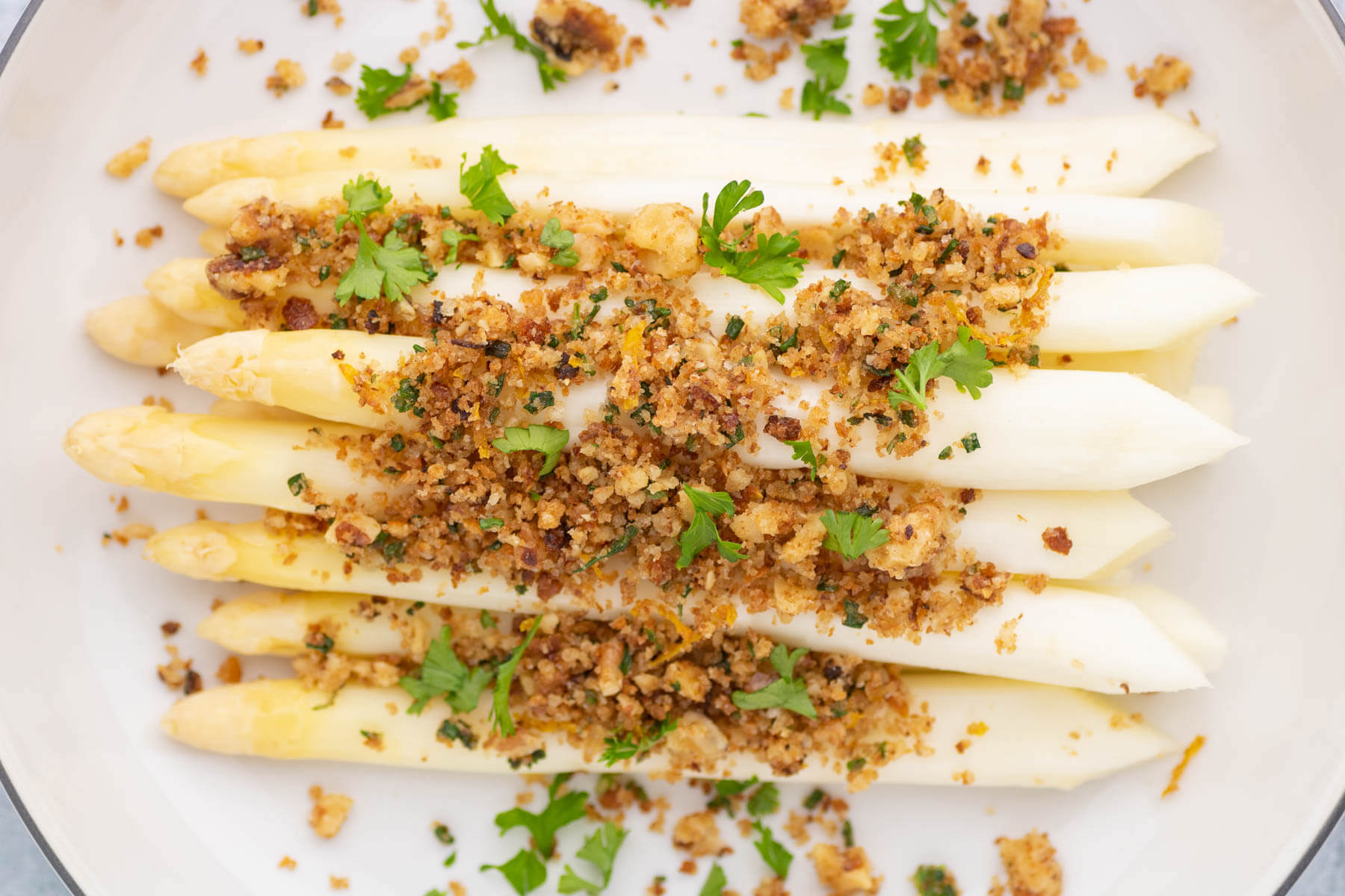 Steamed white asparagus covered in golden pangrattato and herbs.
