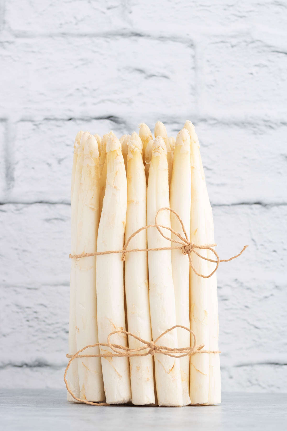 A bundle of raw white asparagus tied with string.