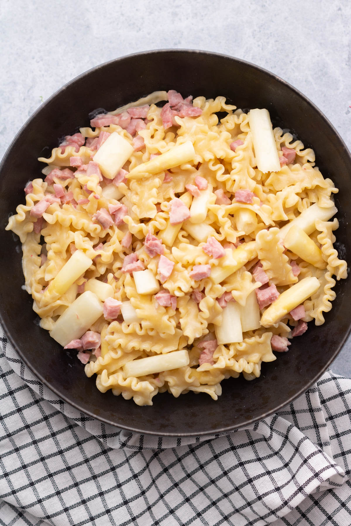 A bowl of lemon butter pasta with ham and white asparagus.