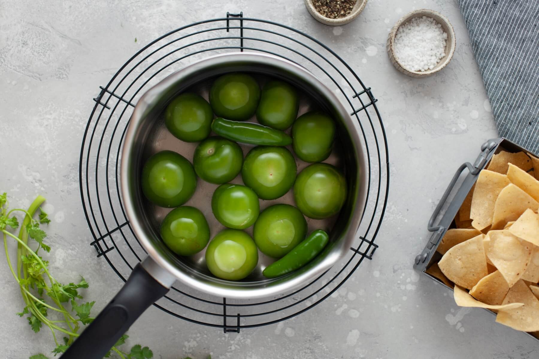 Fresh whole green tomatillos in a pot of water.