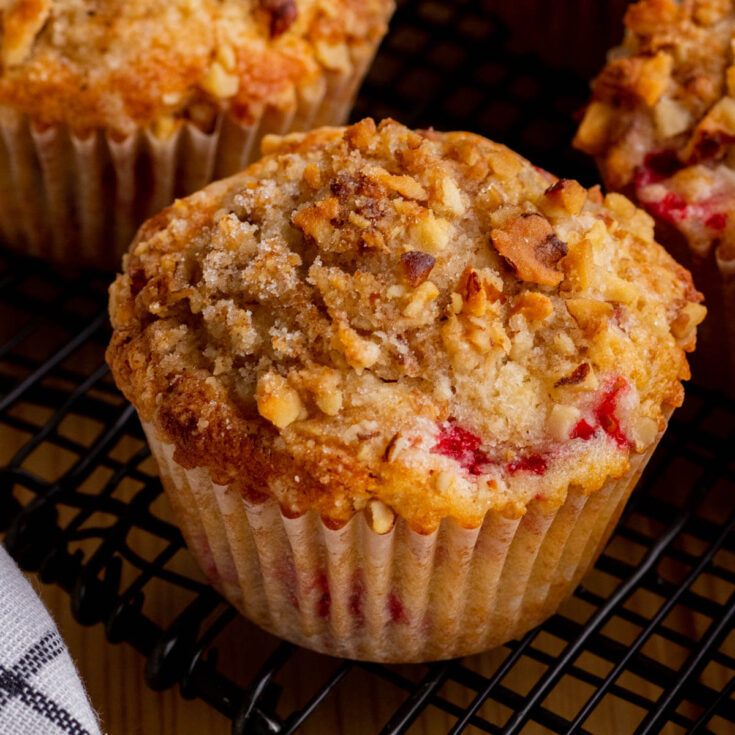 A golden baked strawberry rhubarb muffin topped with streusel.
