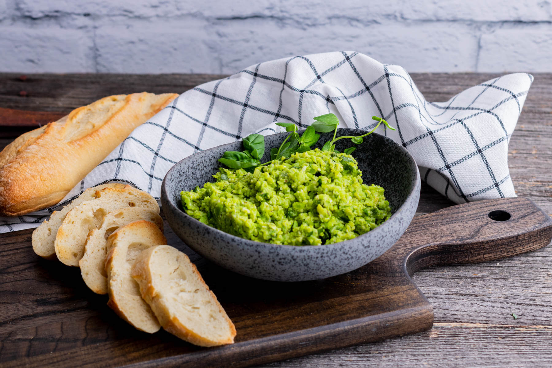 A dark stone bowl filled with bright green fava bean dip.