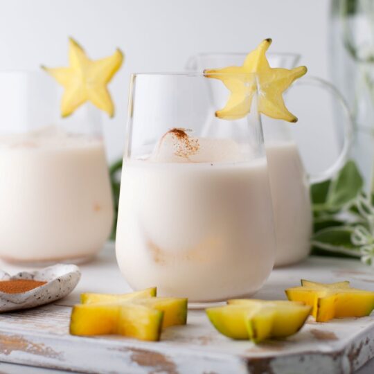 Glasses filled with creamy homemade horchata garnished with a cinnamon stick and starfruit.