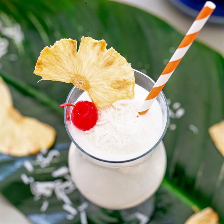 Top view of a Pina Colada garnished with a wedge of pineapple, a cherry, and shredded coconut.