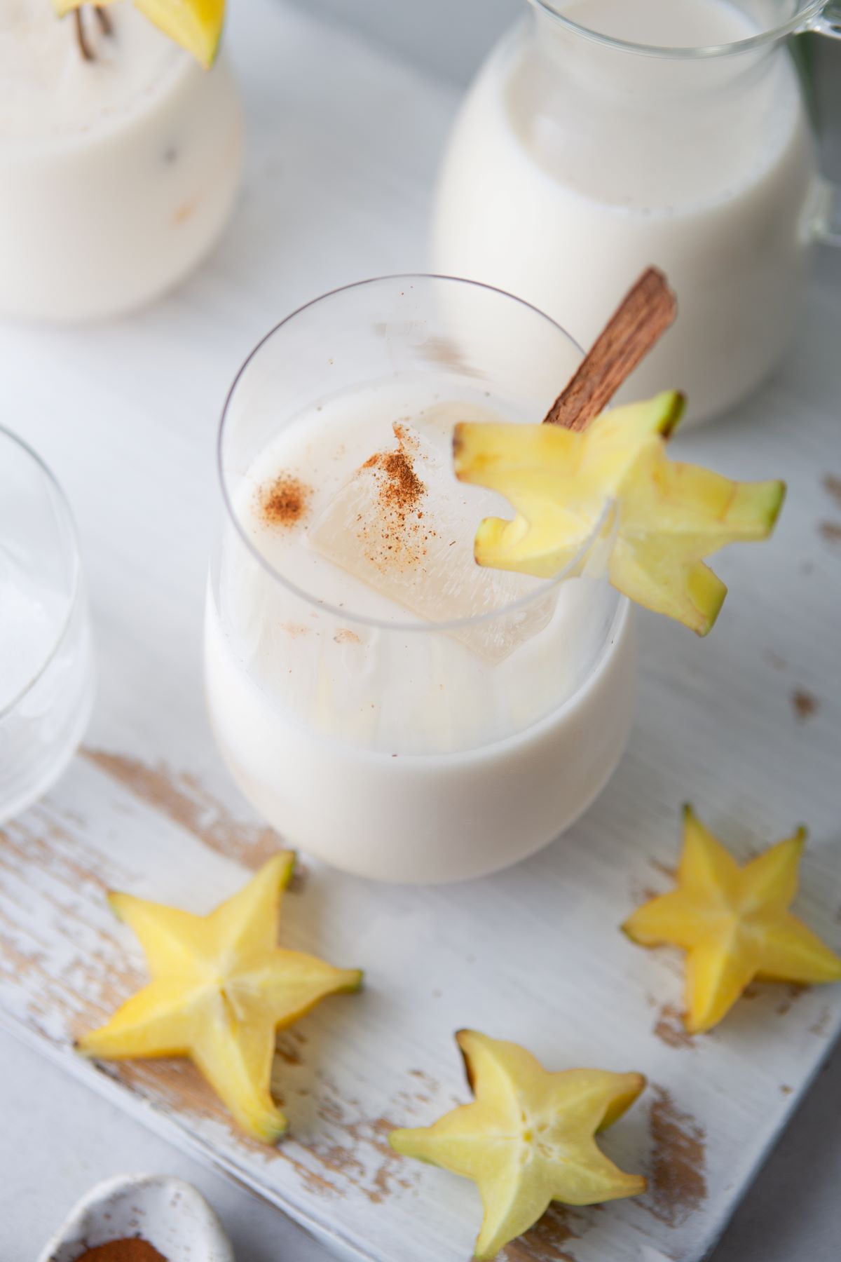 A glass filled with creamy homemade horchata garnished with a cinnamon stick and starfruit.