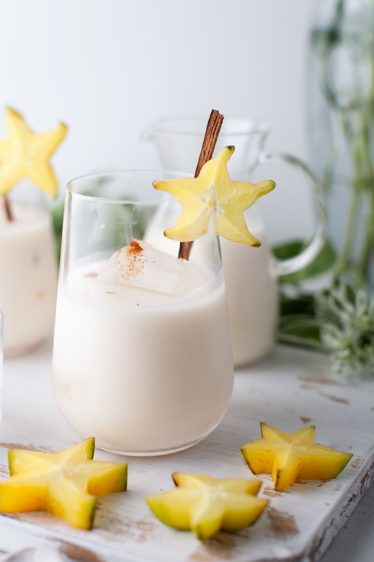 Glasses filled with creamy homemade horchata garnished with a cinnamon stick and starfruit. 