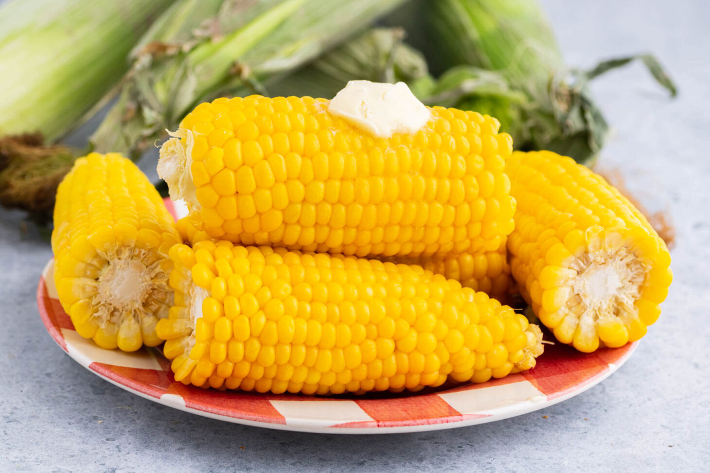 A plate full of golden yellow stack of cooked Instant Pot Corn on the Cob.