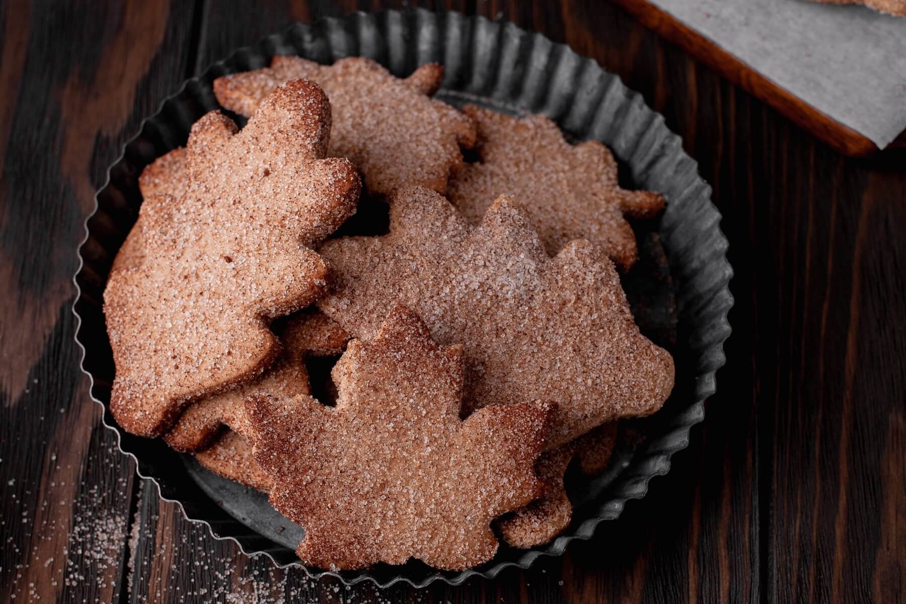 A tin plate filled with leaf shaped Walnut Cookies coated in cinnamon sugar.