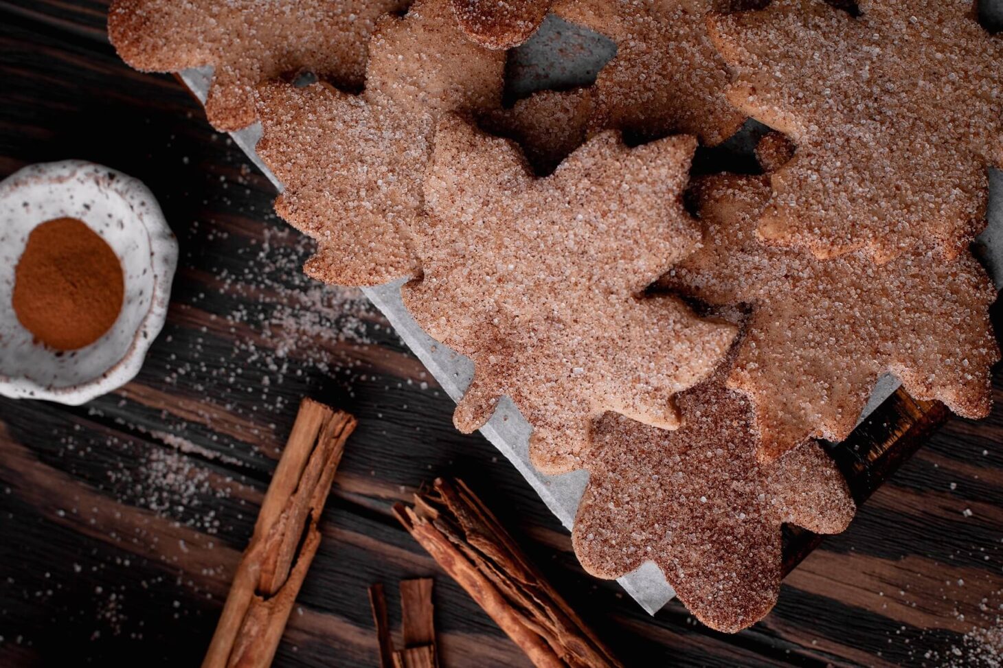 Parchment paper covered with leaf shaped Walnut Cookies coated in cinnamon sugar.