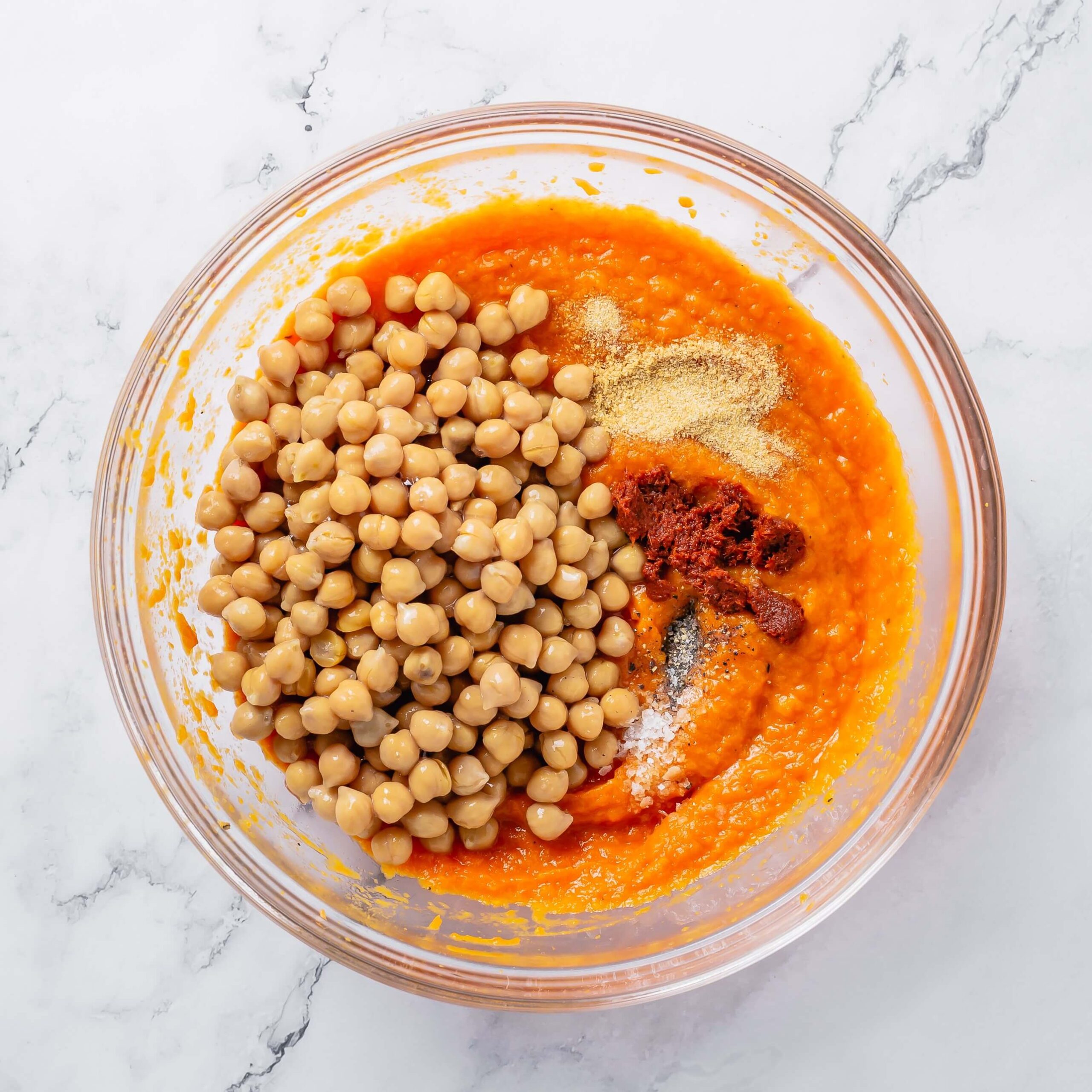 A glass bowl containing the ingredients for pumpkin hummus.