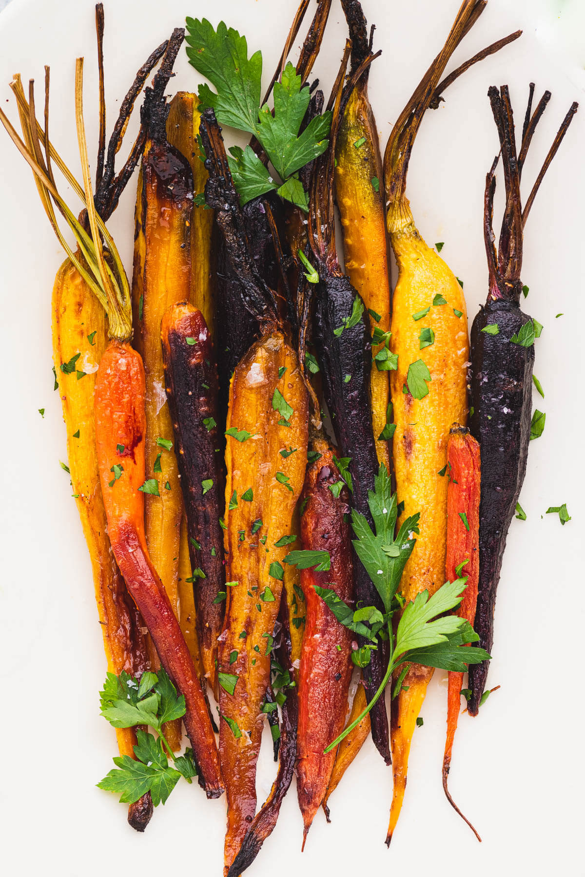 Colourful Maple Balsamic Roasted Carrots garnished with coarse salt and chopped parsley.