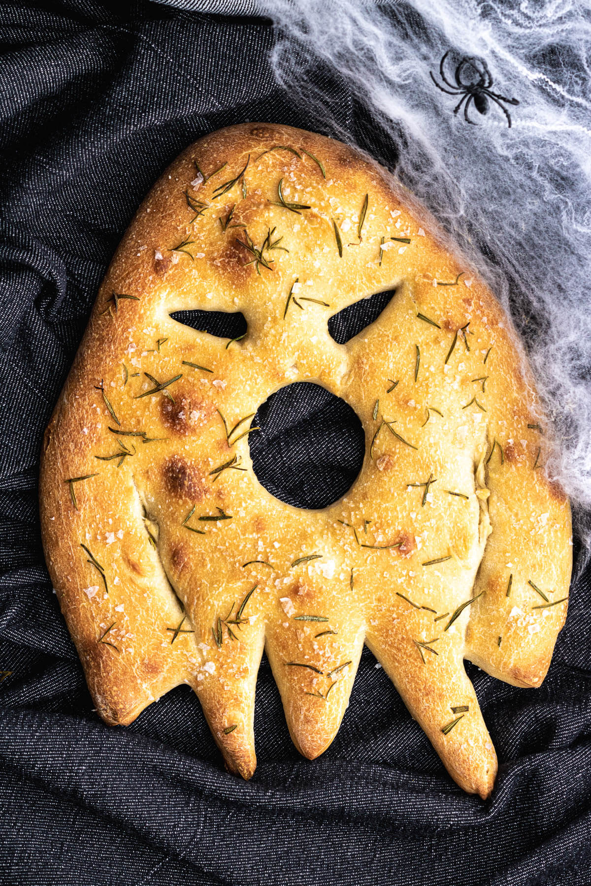 A ghost shaped fougasse flat bread with a skeleton hand covering the open mouth.