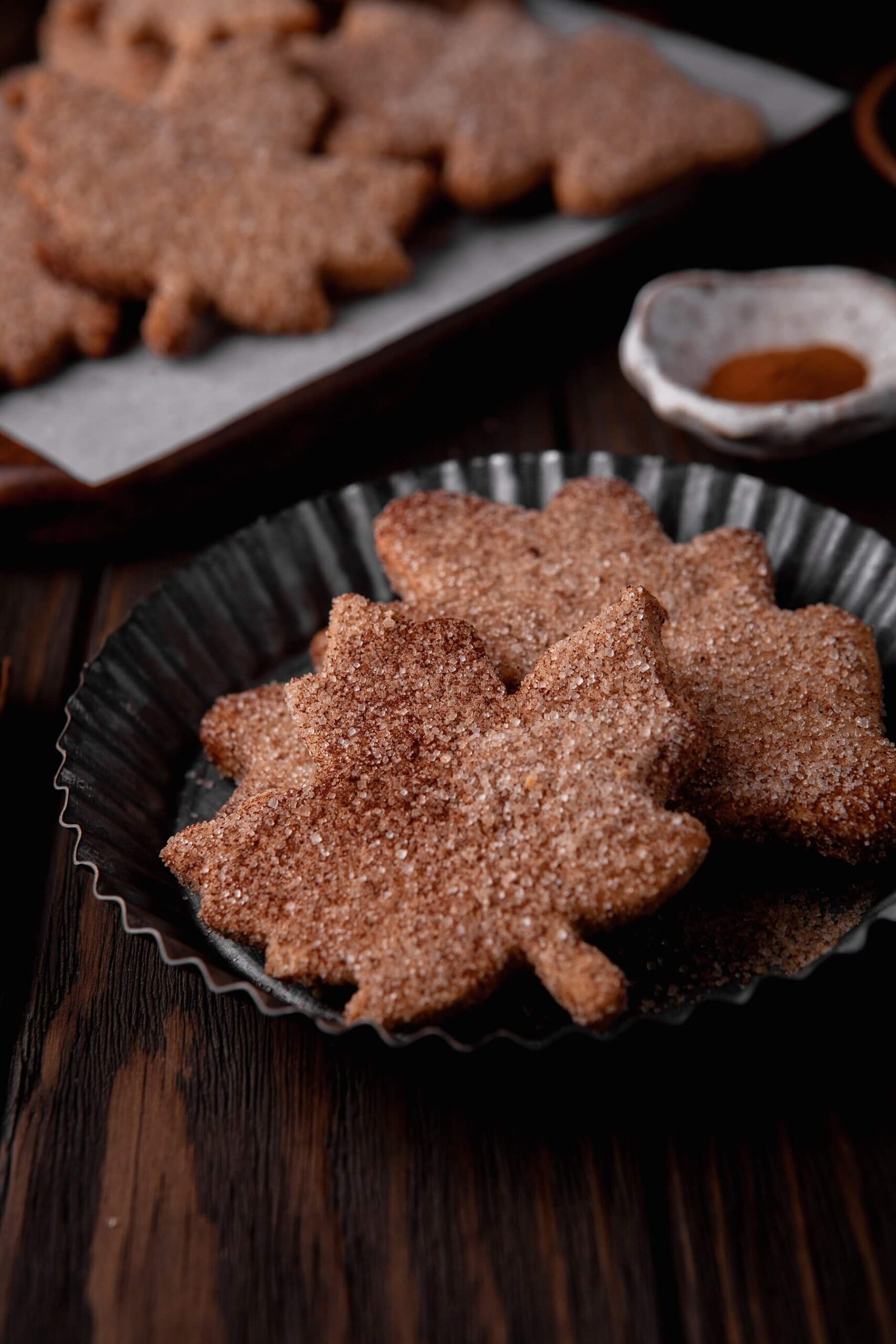 A tin plate filled with leaf shaped Walnut Cookies coated in cinnamon sugar.