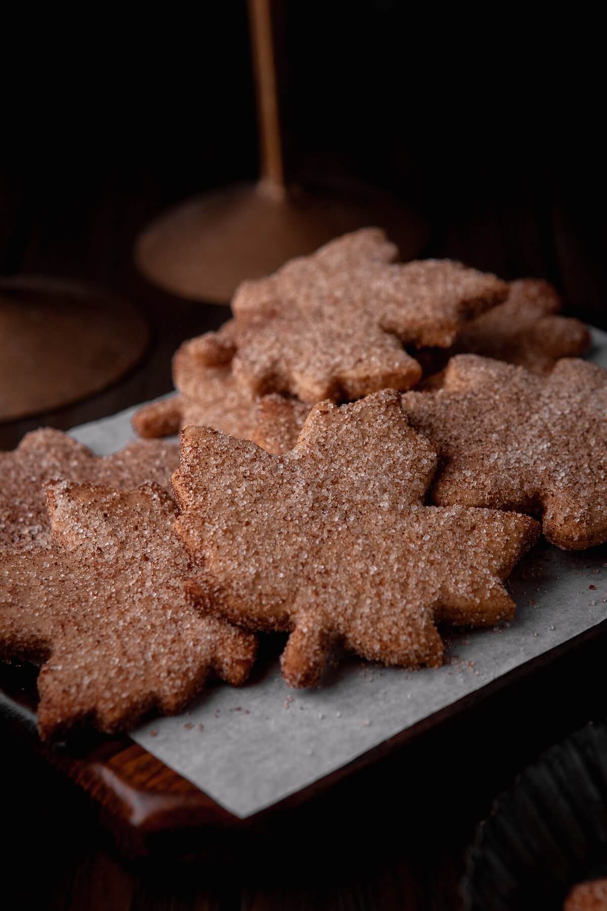 Parchment paper covered with leaf shaped Walnut Cookies coated in cinnamon sugar.