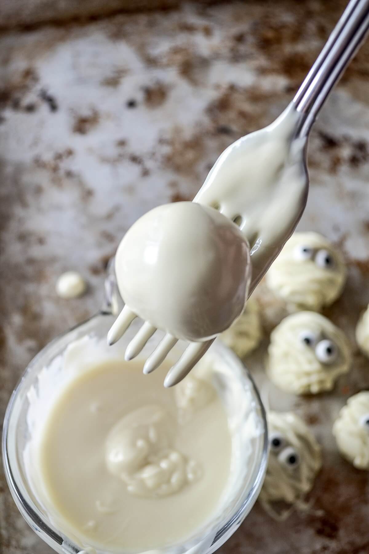 Allowing excess white chocolate to drip from a freshly dipped oreo truffle.