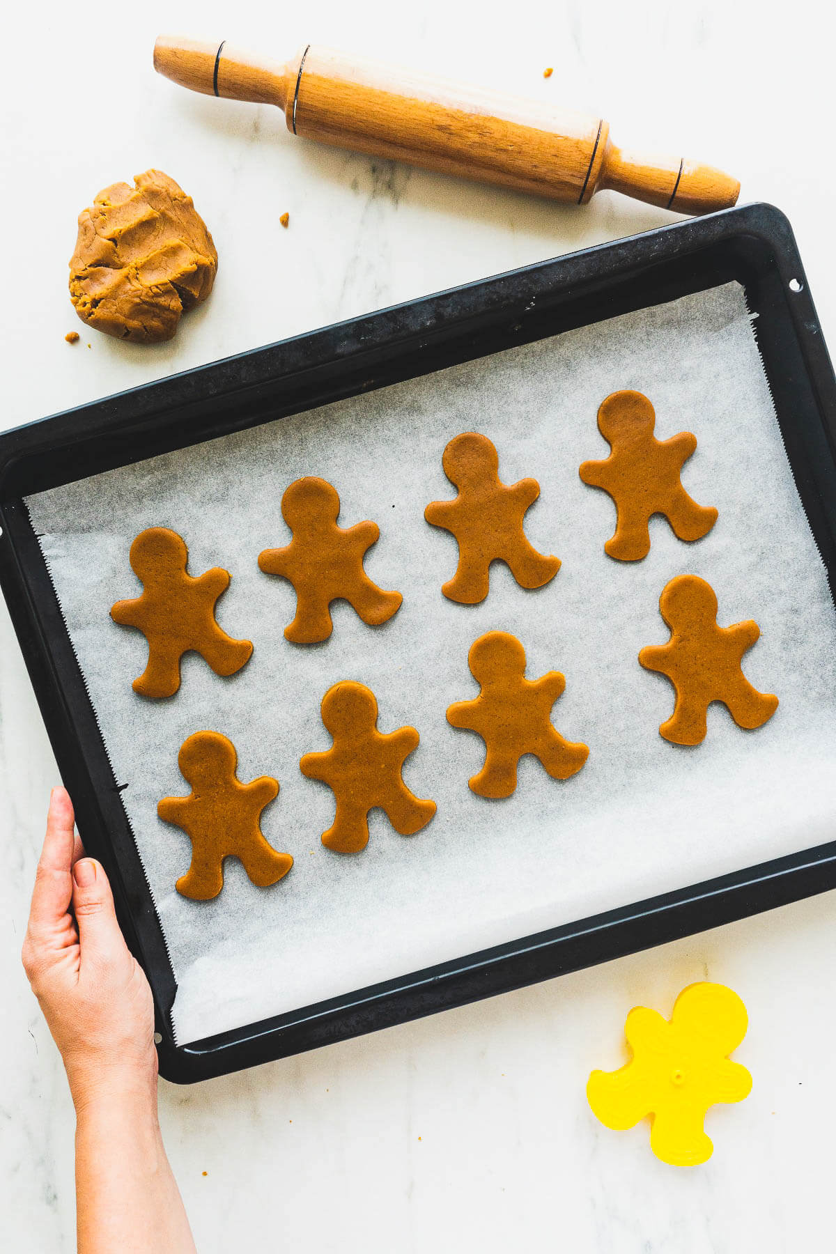 A baking sheet full of unbaked gingerbread cookies on parchment paper.