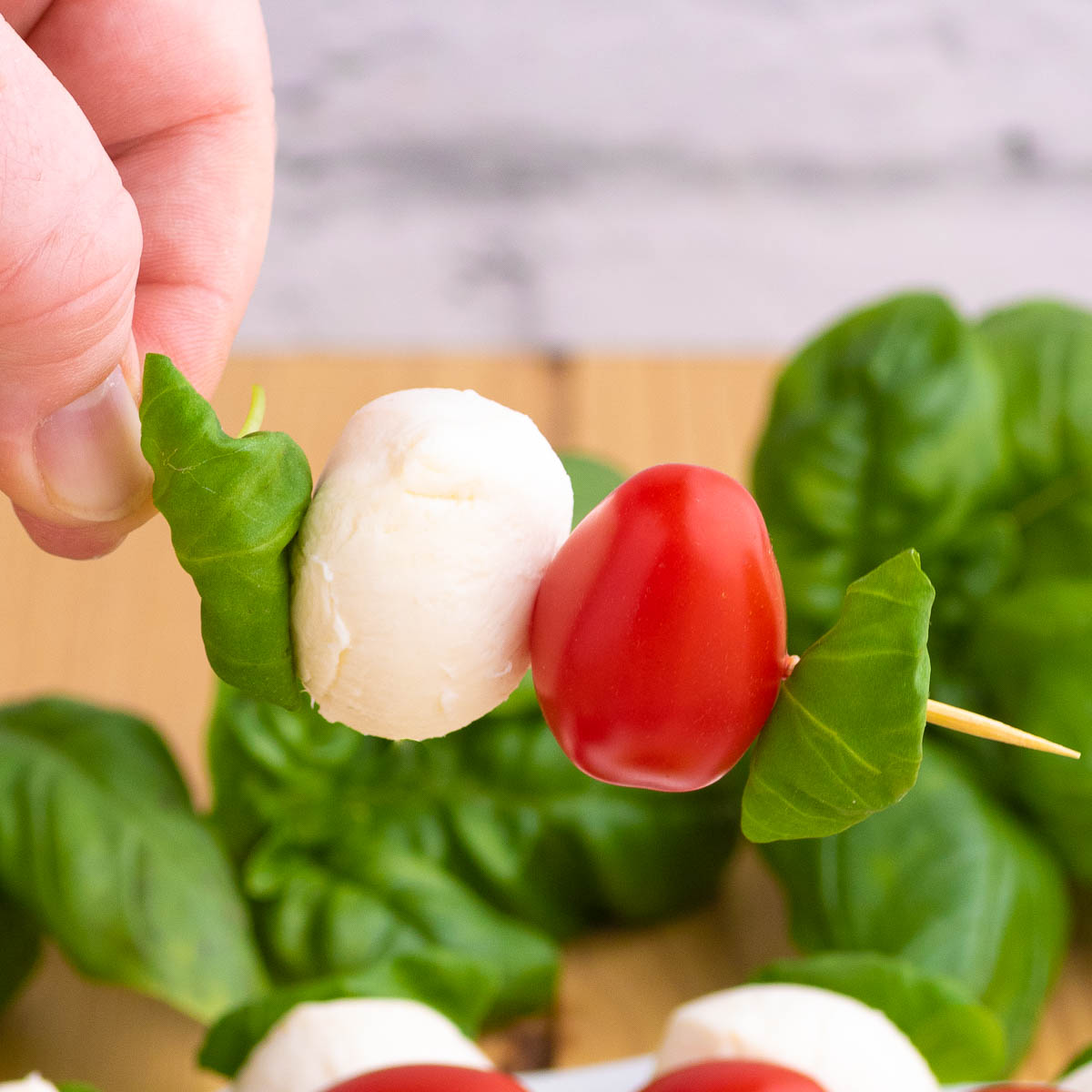 A hand holding on to a caprese salad skewer.