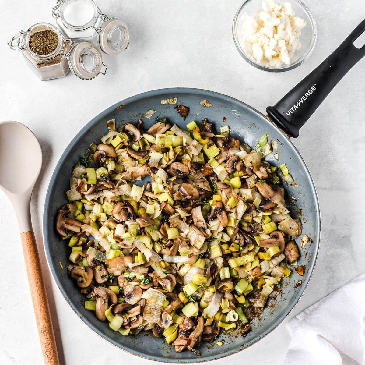 A frying pan filled with chopped leeks and mushrooms.